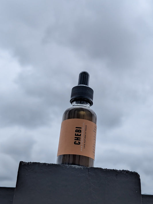 Bottle with a dropper labeled 'Chebi Oil' against a cloudy sky